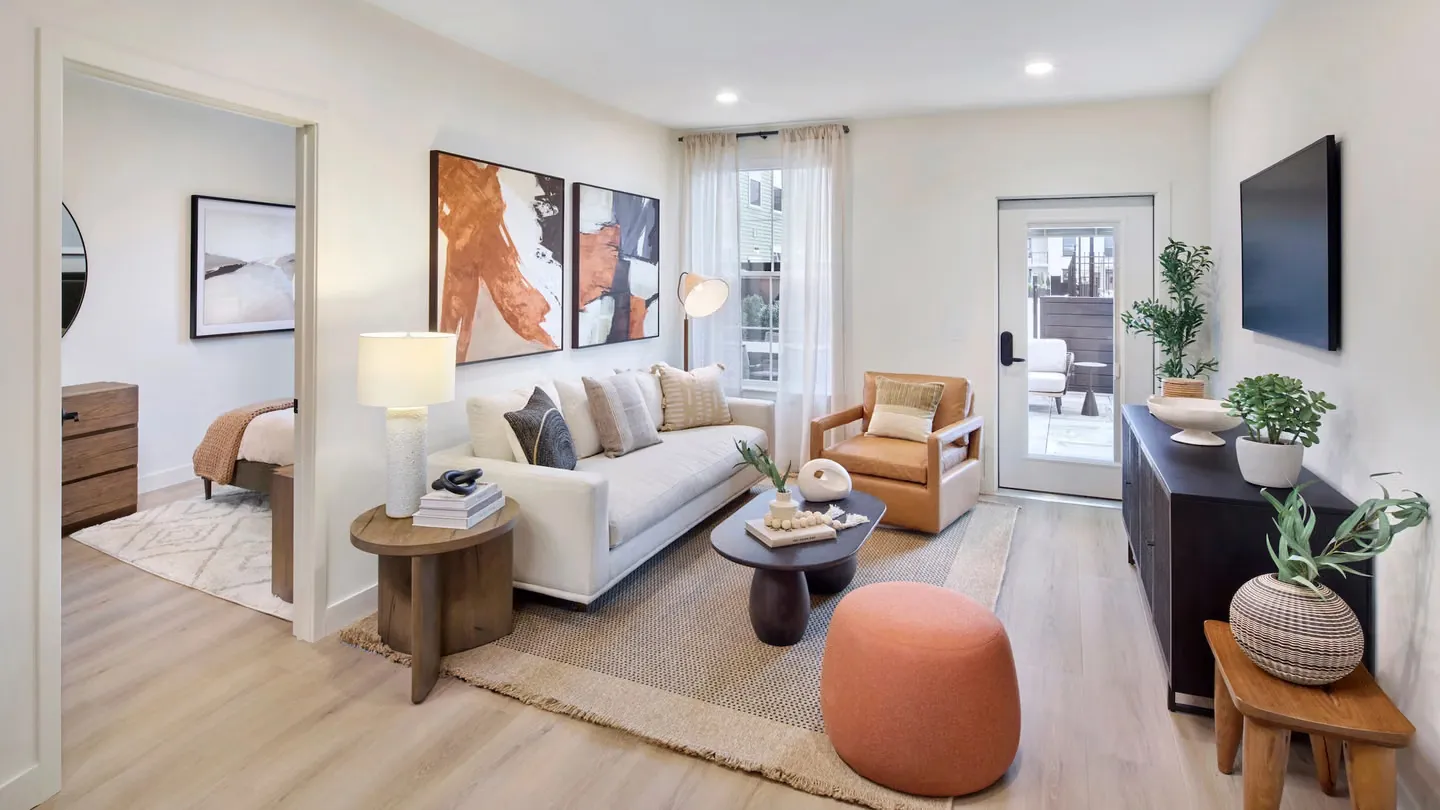 Modern open-concept kitchen and living room with wood floors, island seating, and large windows.