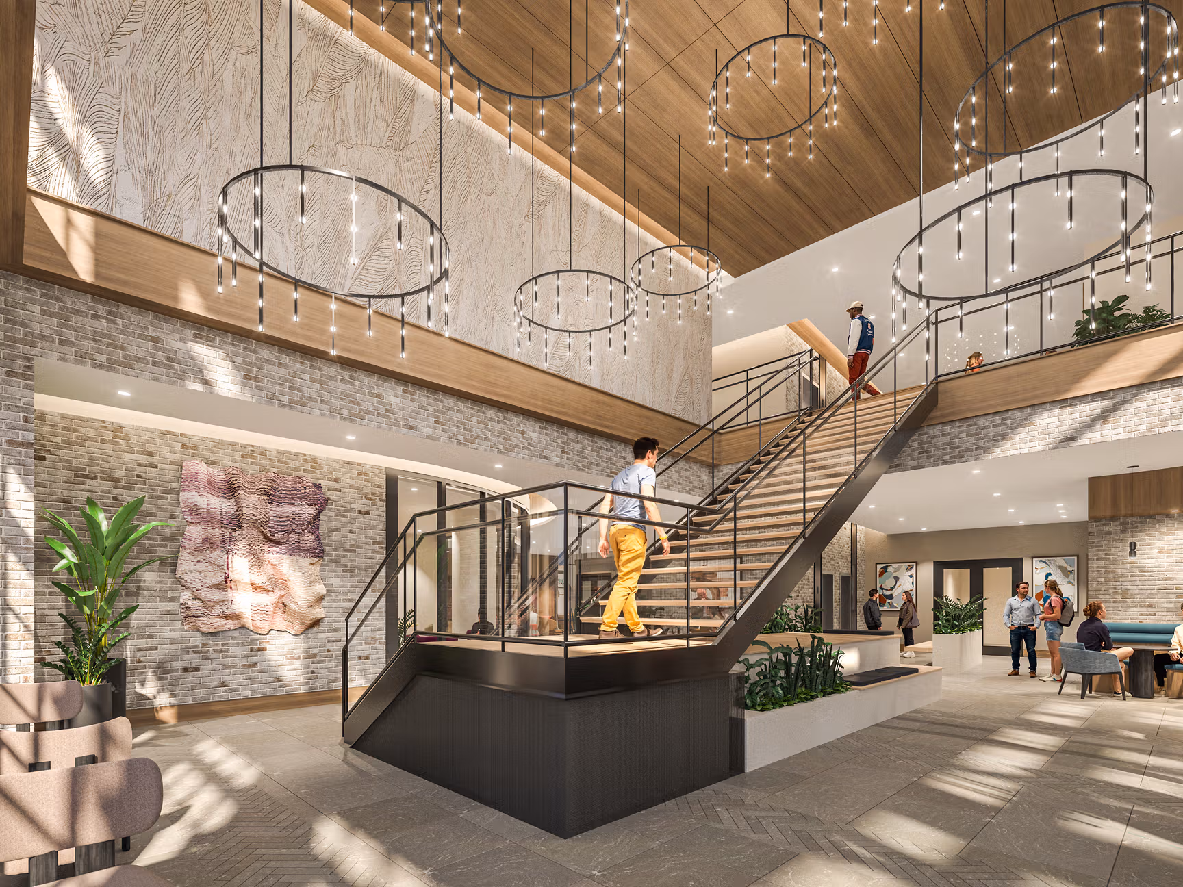 Spacious lobby with grand staircase, modern lighting, brick walls, and people interacting casually.
